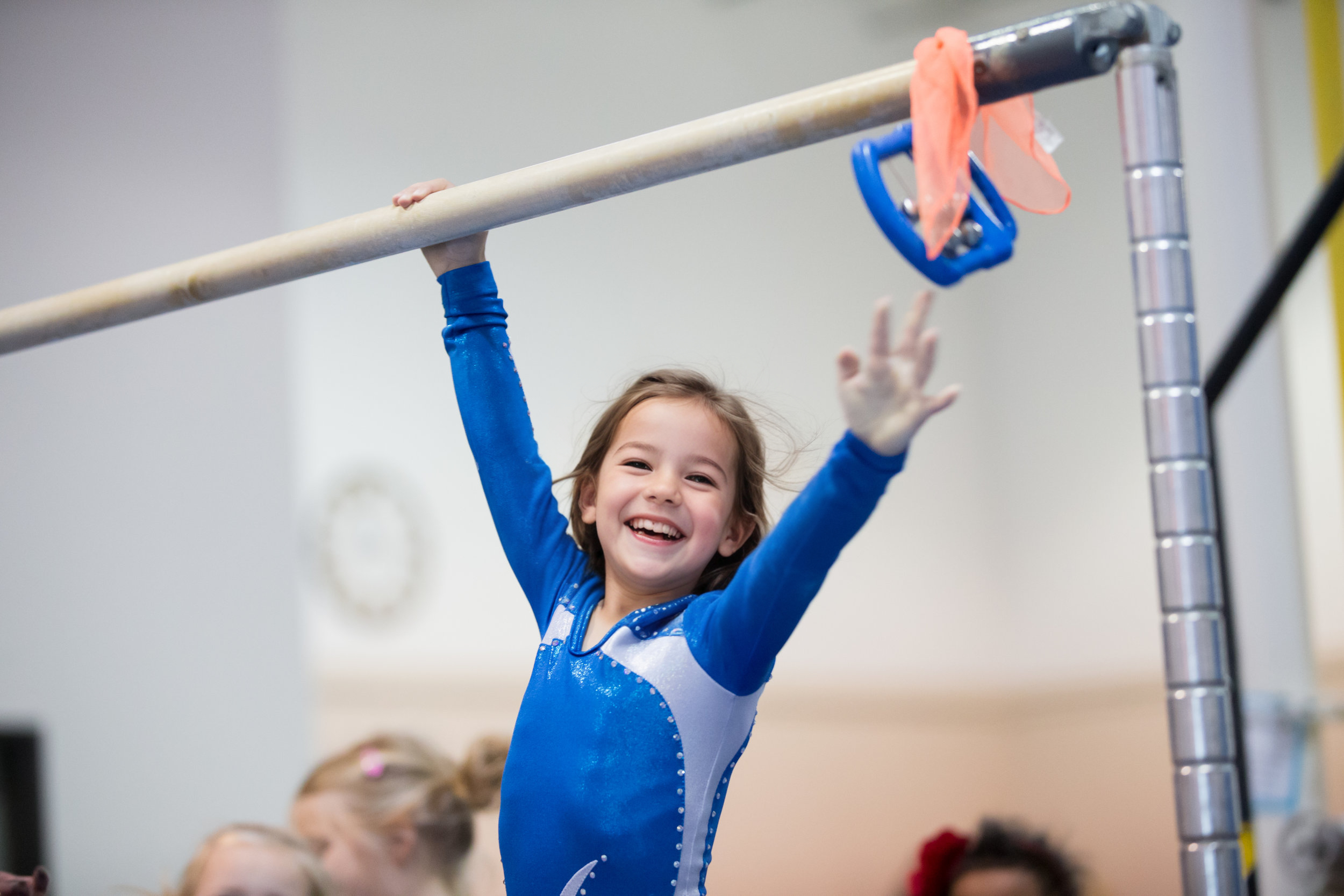 Girl smiling reaching for the high bar